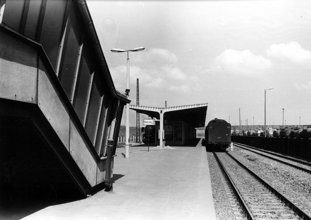 Bahnhof Buna-Werk.jpg - Bahnhof Buna-Werke vor 1967. Links ist heute nach wie vor der Rangierbahnhof  des Buna Werkes und das Heizkraftwerk von Buna. In der Bildmitte ist ein Fahrleitungsmast zu sehen, da ab 1967 Schichtarbeiterzüge aus Halle-Neustadt über die neue Strecke kamen muss die Aufnahme davor entstanden sein. Für diese neue Verbindung wurde die Strecke Angersdorf - Bad Lauchstädt hiner den Bahnhof Holleben nach Bad Lauchstädt gekappt und neu verlegt bis zum Buna Werk. Die komplette Strecke ist bis Merseburg elektriefiziert worden. Wobei auch eine Verbindung von Halle-Neustadt nach auf die von Angersdorf kommende Strecke geschaffen wurde. Heute ist von der Bahnsteigüberdachung nichts mehr vorhanden. Heute fahren nur noch Triebwagen von Merseburg nach Schafstädt und zurück. Die Verbindung von Merseburg über das Buna-Werk nach Halle-Neustadt, ohne zwischenhalt, ist eingestellt. Die Strecke wird nur noch für den Güterverkehr genutzt.Da es sich bei diesen Bild um ein Fund aus ehm. DR-Bestand handelt, kann ich keine weiteren Angaben zu diesen Foto machen.