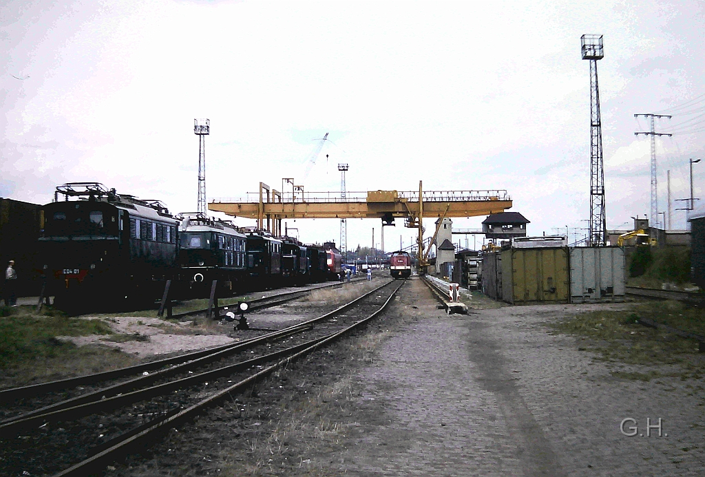 Ga-Halle_Containerumschlag_Hg9_25.04.1992.01(2).JPG - Aus Anlass 25. Jahre S-Bahnbetrieb in Halle gab es auf der GA (Güterabfertigung) Halle eine Fahzeugschau am 25. April 1992. Diese Ausstelung fand auf den Cotainerbahnhof statt, daher sind auch die beiden Verladekräne für die Container zu sehen. In der rechten Bildhälfte ist im Hintergrund ist das Brückstellwerk Hg 9 zu sehen. Im übrigen geht von den Stellwerksgebäude eine Brücke zu den links daneben stehenden Turm und war der Zugang zum Stellwerk. Das Stellwerk selber war das Ablaufstellwerk für den Südberg des Güterbahnhof Halle.